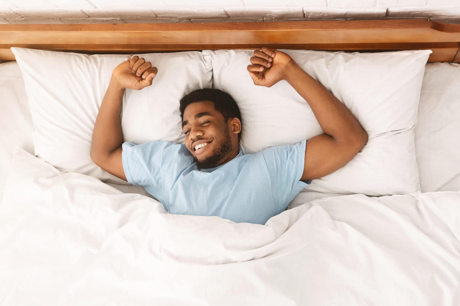 a young man happily sleeping on a bed