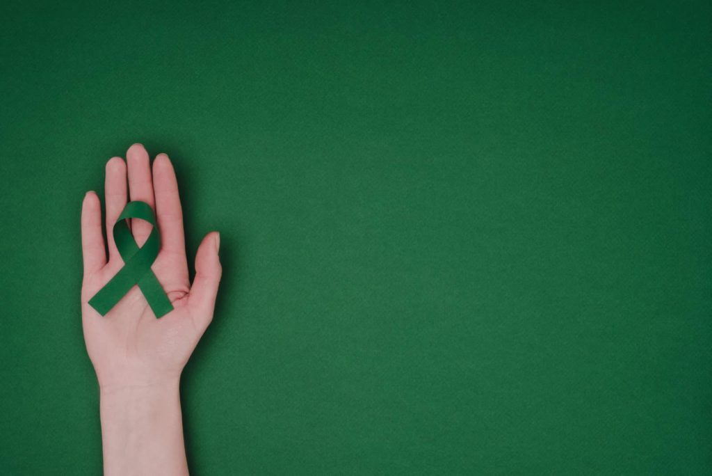 green ribbon on a palm signfying scoliosis awareness