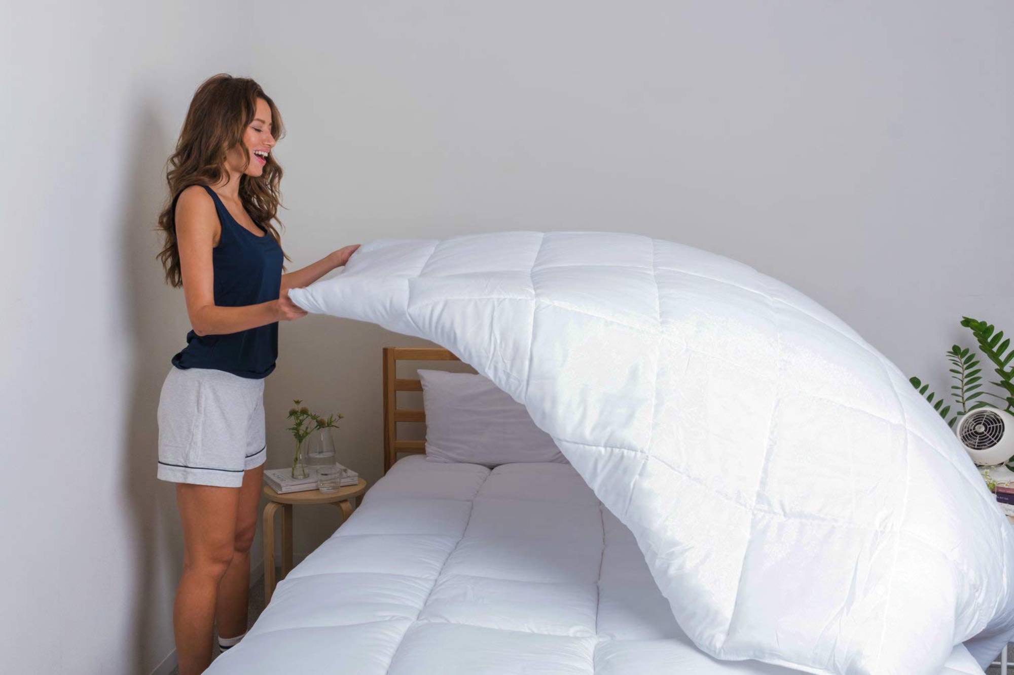 a woman placing a mattress topper on her bed