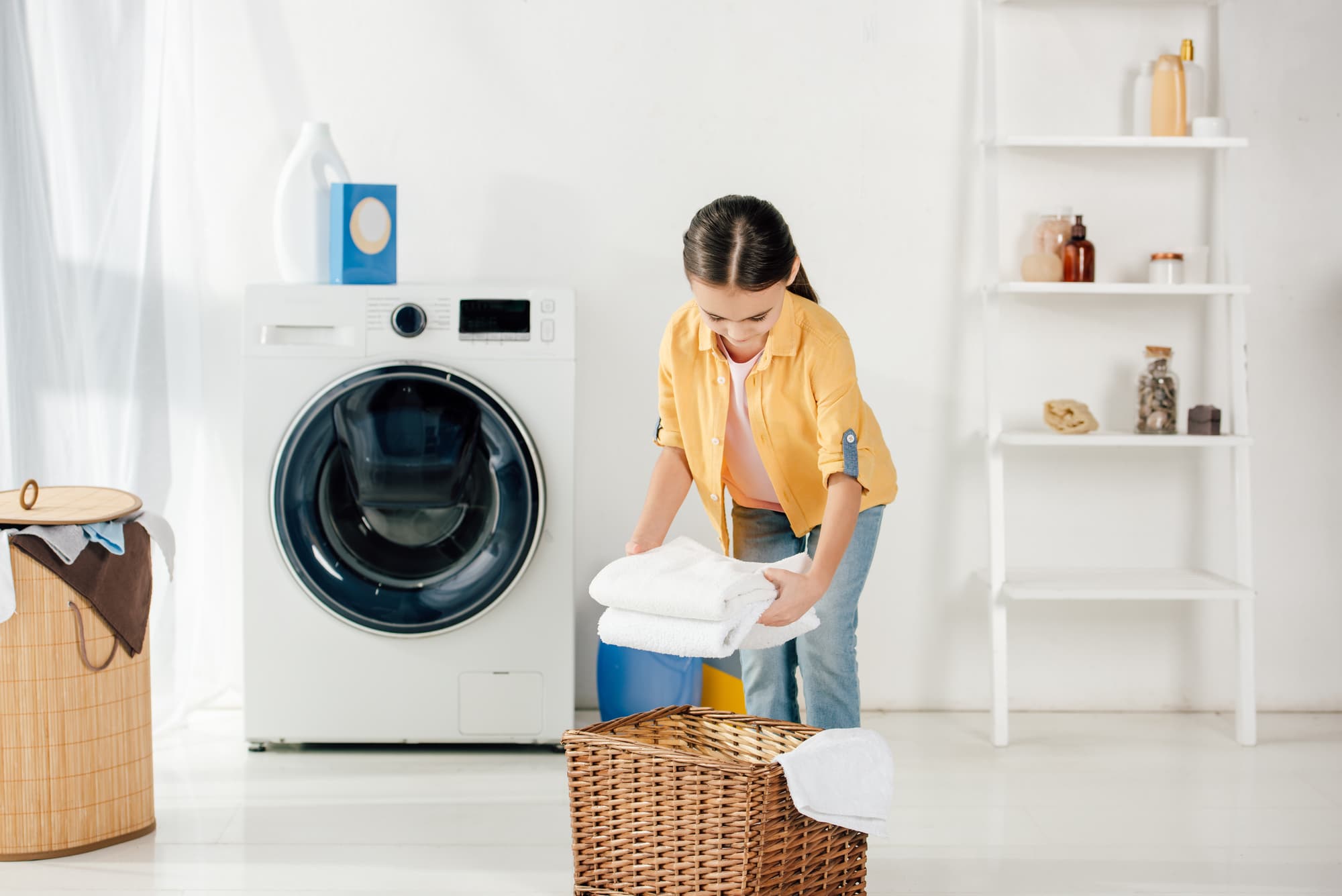 a child putting some towels in a laundry basket