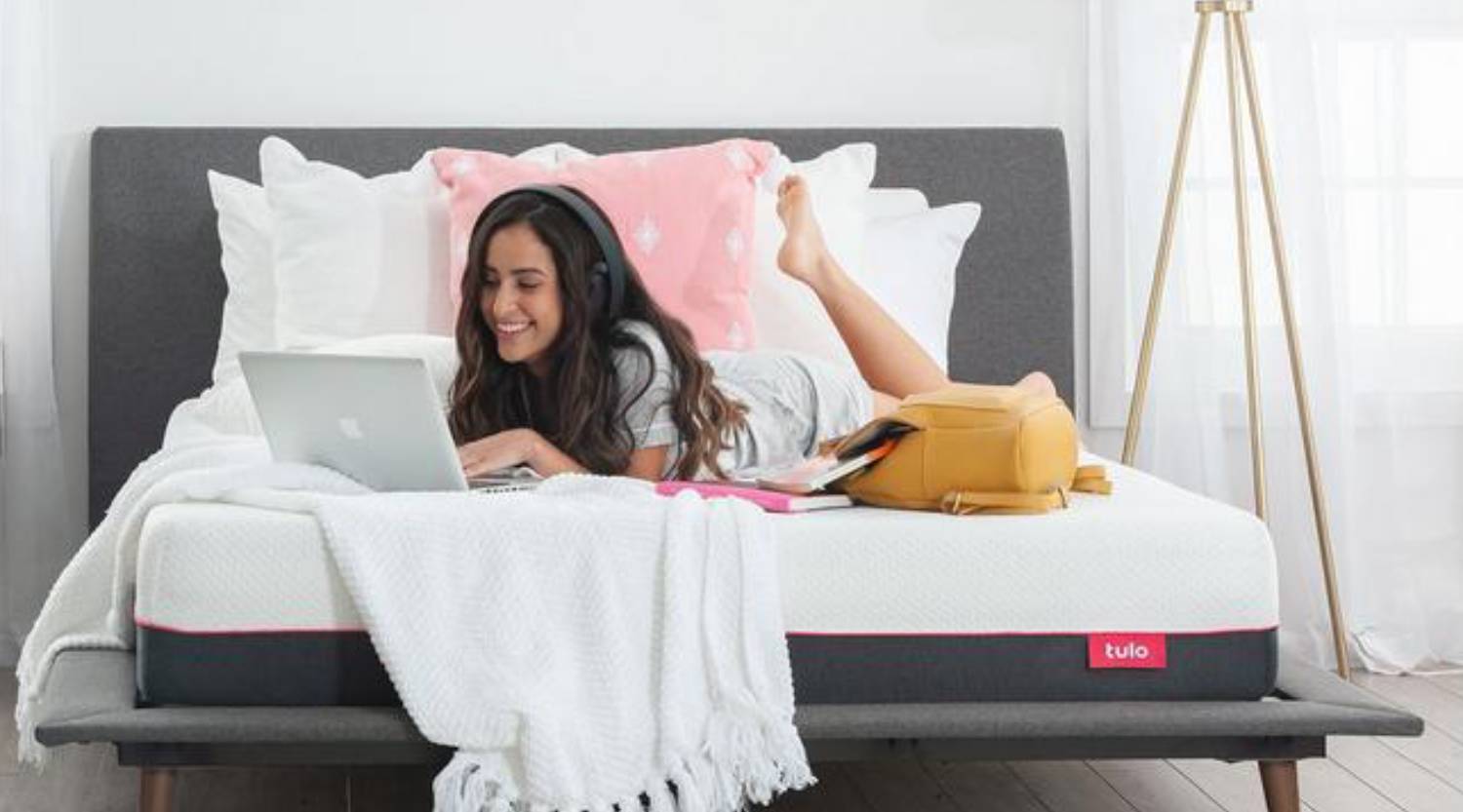 a young lady resting on her bed with a laptop