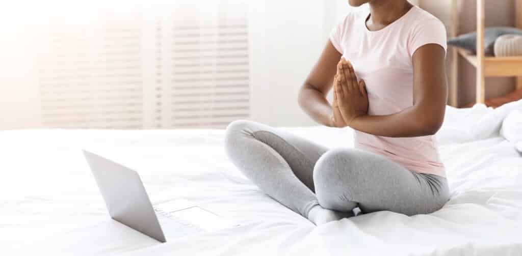 black woman having online meditation in bed