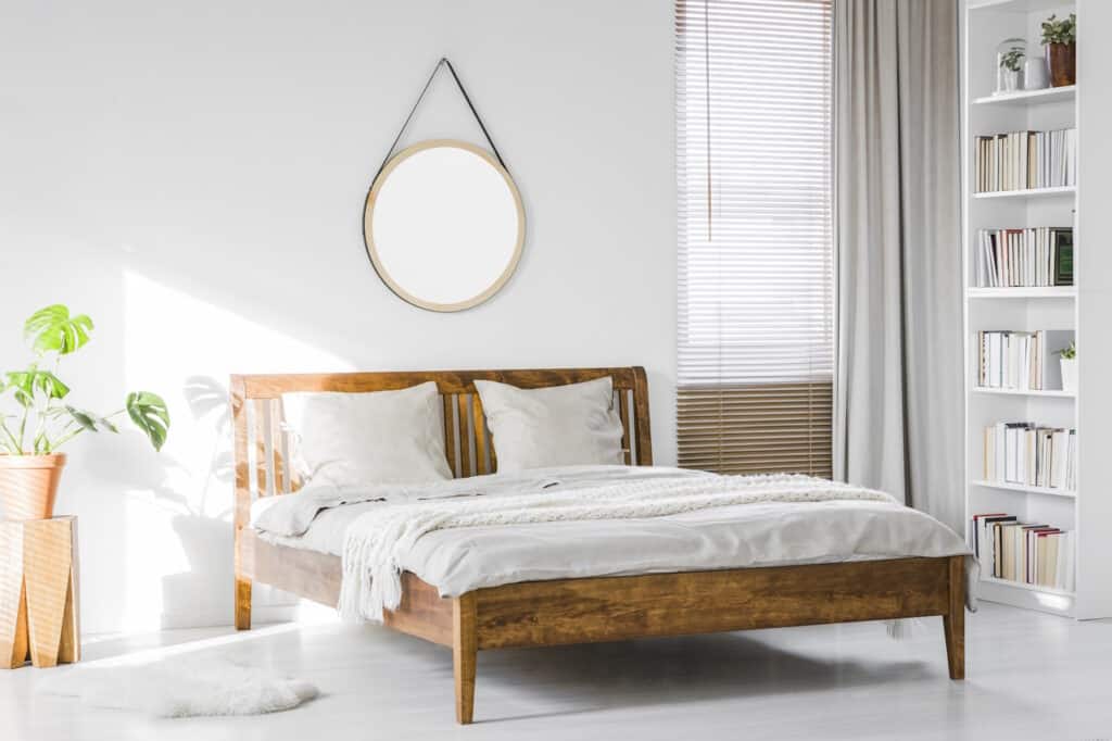 A wooden bed frame in a boho bedroom